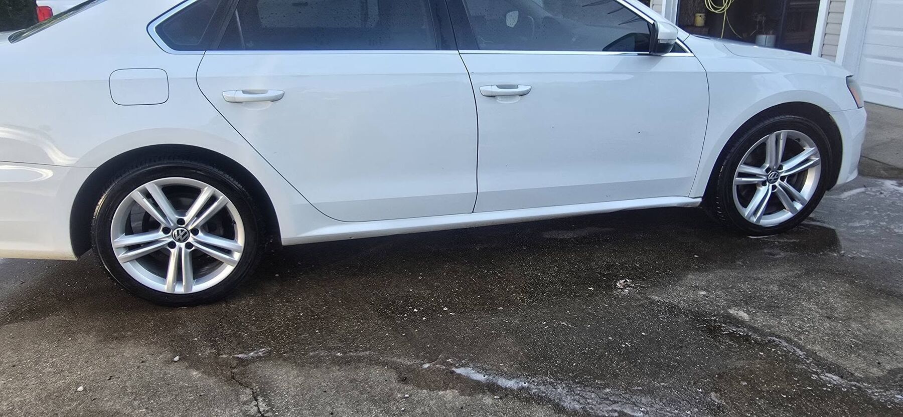 White Volkswagen sedan, freshly washed in a driveway
